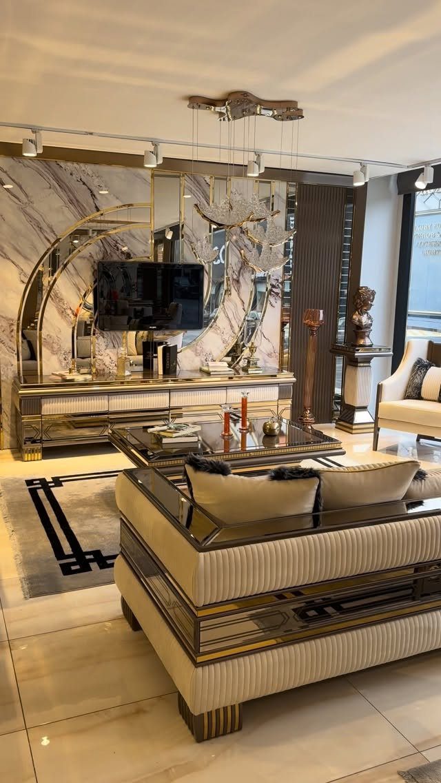 Luxurious living room with beige gold-trimmed sofa, glass table, and marble accent wall.