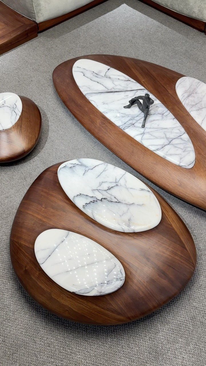 Organic shaped wooden coffee tables with white marble inlays on a grey carpet