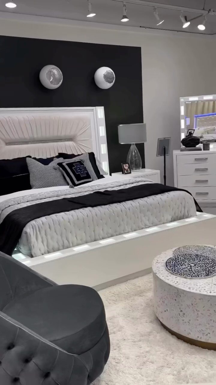 Modern white bed with illuminated frame and grey tufted chair in bedroom