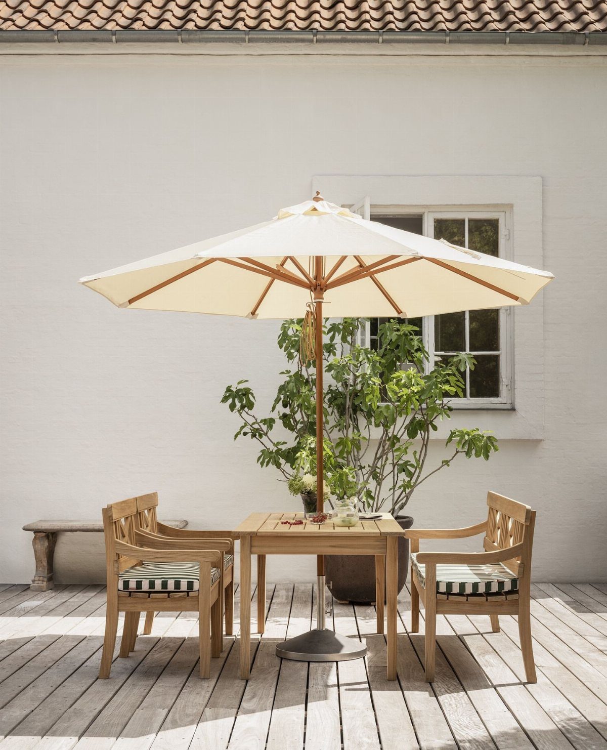 Cream patio umbrella over a wooden dining set on a light wood deck.