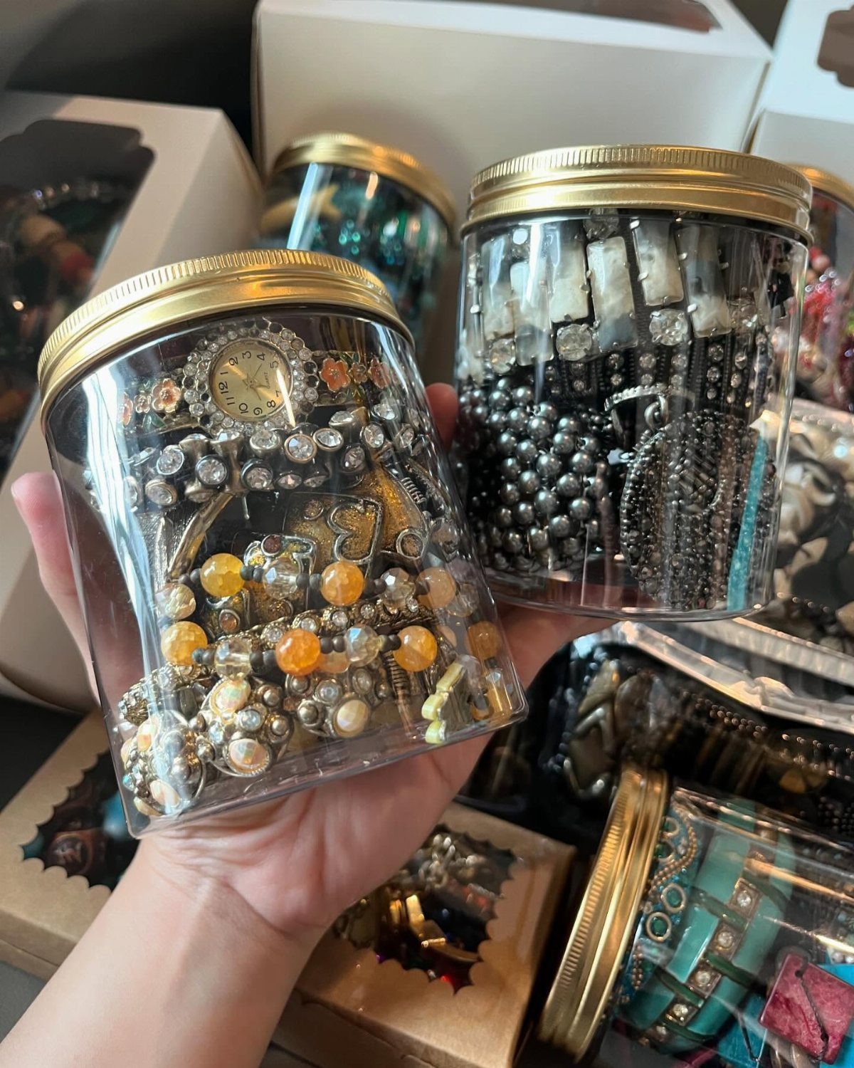 Clear plastic jars with gold lids used to store gold and silver jewelry.