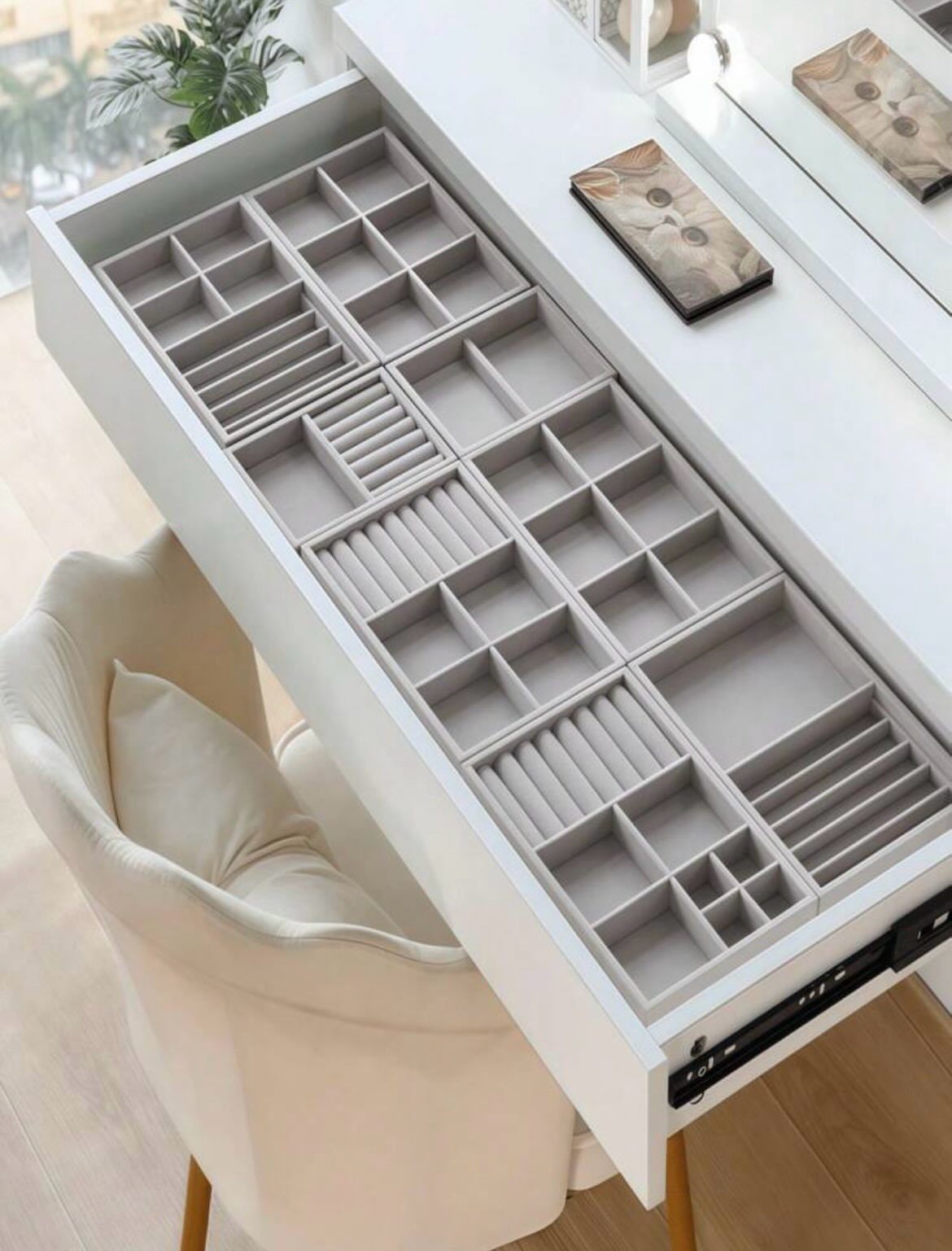 Grey velvet jewelry organizer insert inside an open white desk drawer.