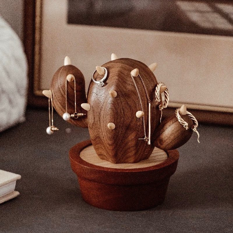 Wooden cactus jewelry holder with gold rings and necklaces in a small pot