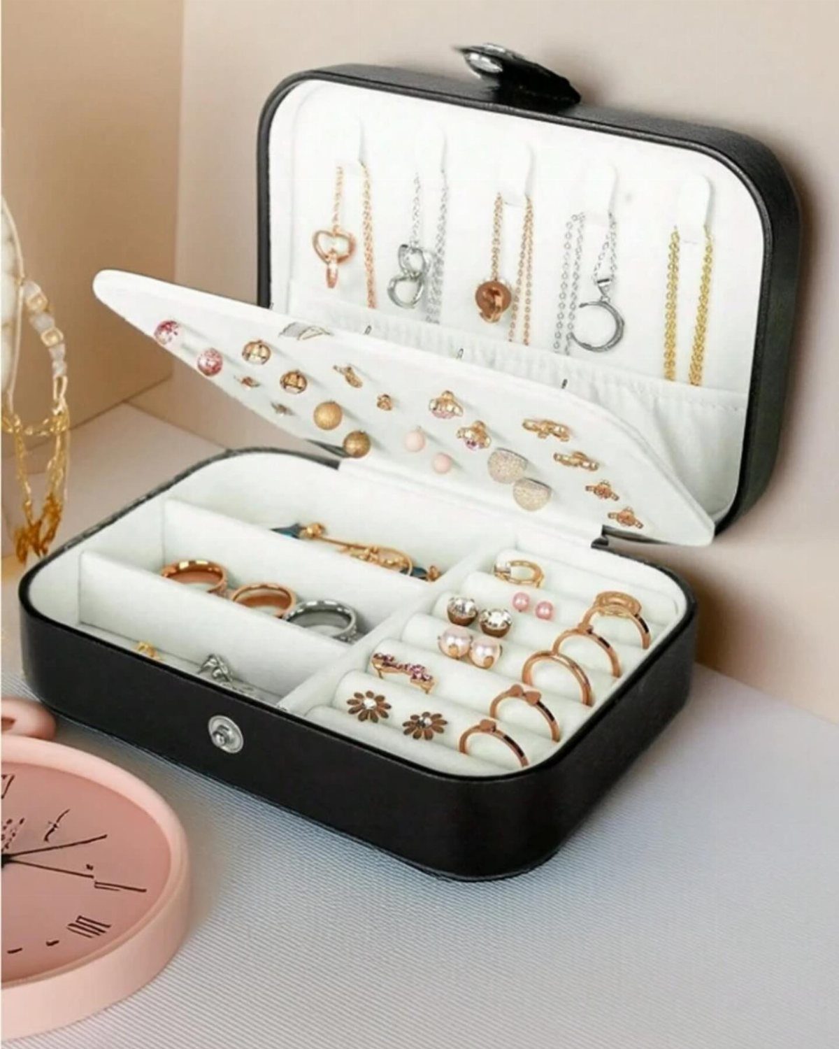 Black travel jewelry case open and filled with rings, necklaces, and earrings.