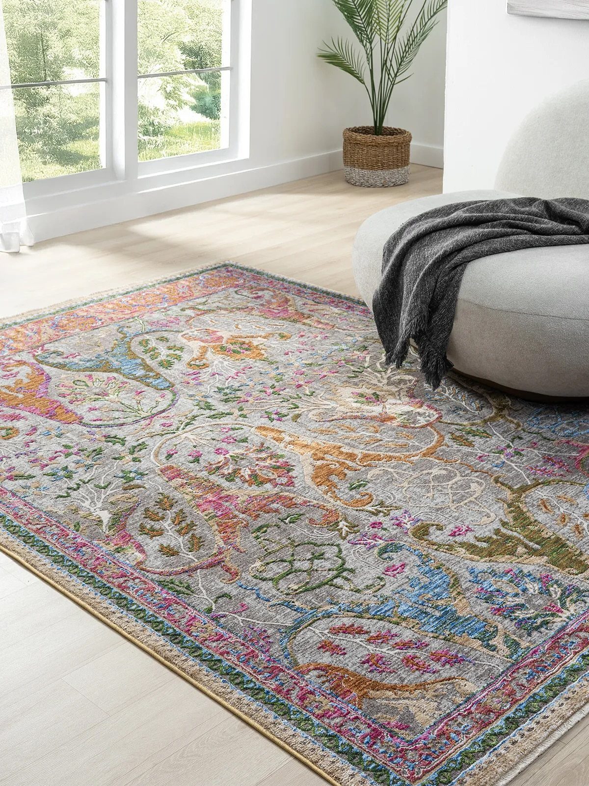Colorful patterned area rug with floral motifs on a light wood living room floor.