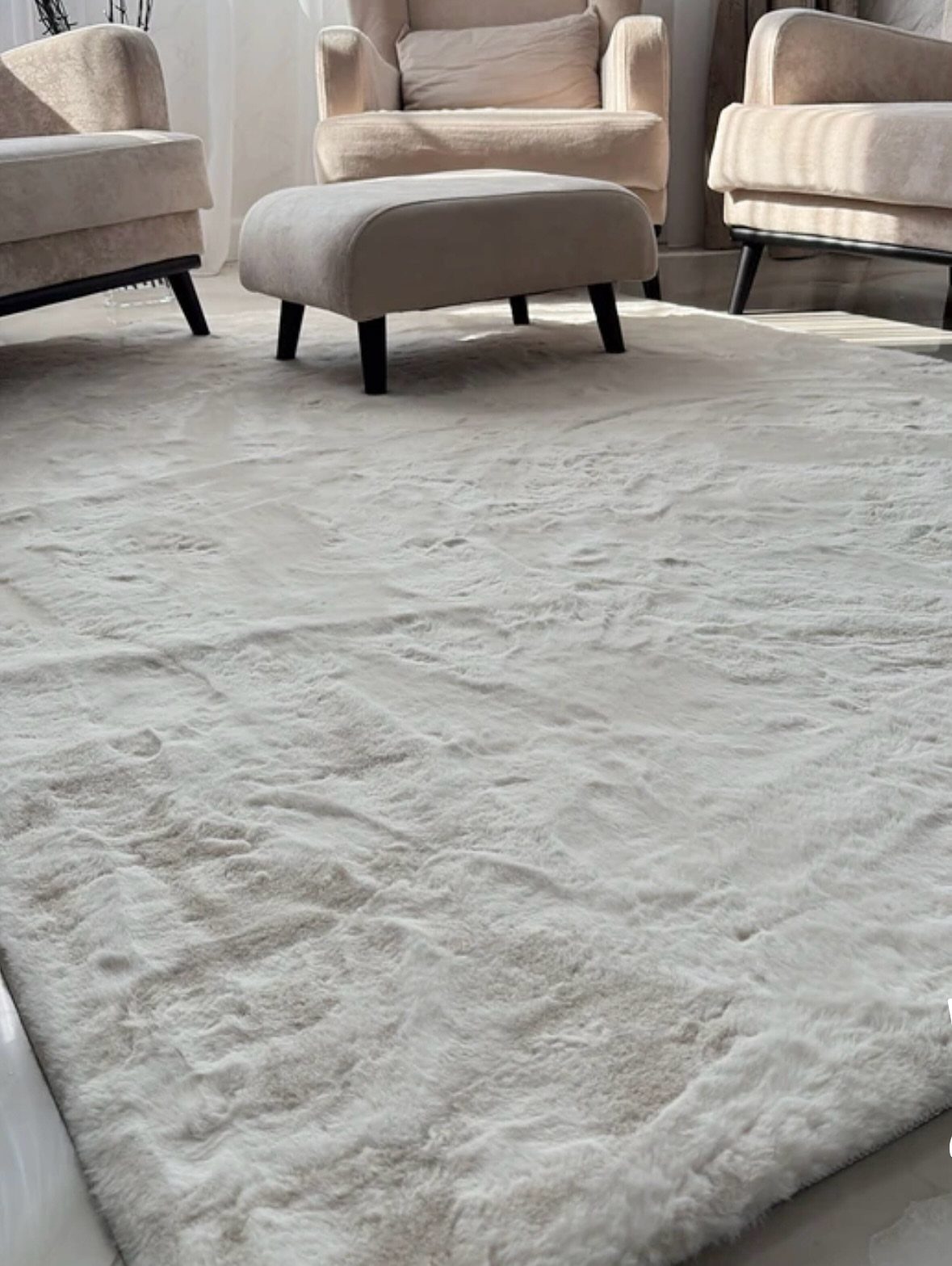 Soft white shag carpet with a matching ottoman and beige tailored armchairs.