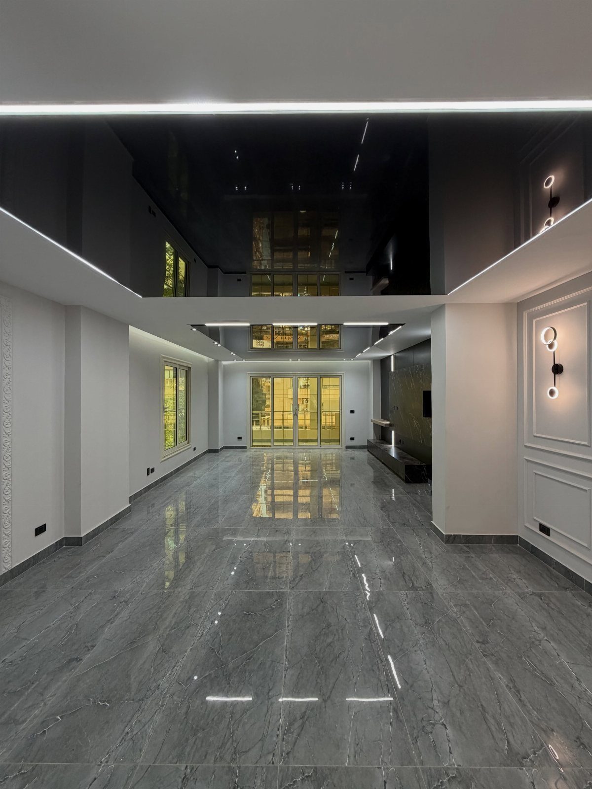 High-gloss black reflective ceiling with linear lighting in a modern marble living room.