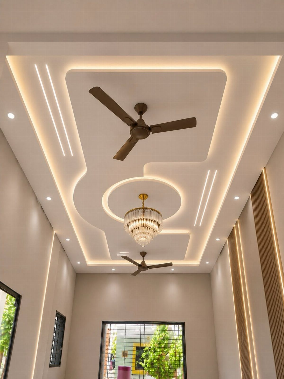 Modern white tray ceiling with recessed LED lighting, crystal chandelier, and brown fans.