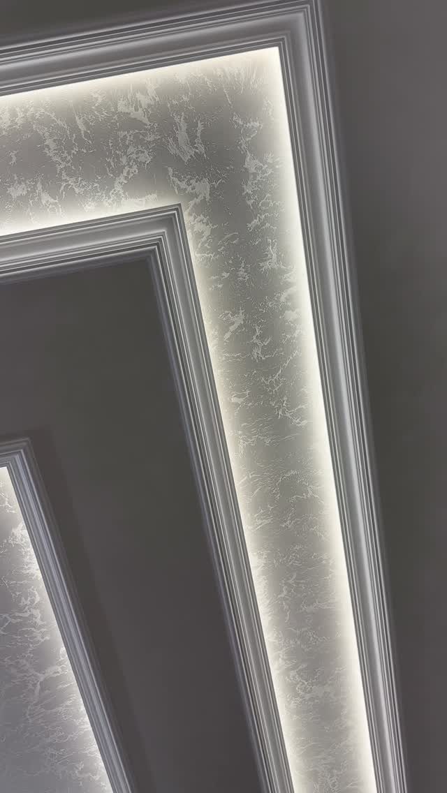 Multi-level tray ceiling with white molding and illuminated textured plaster recessed panels.