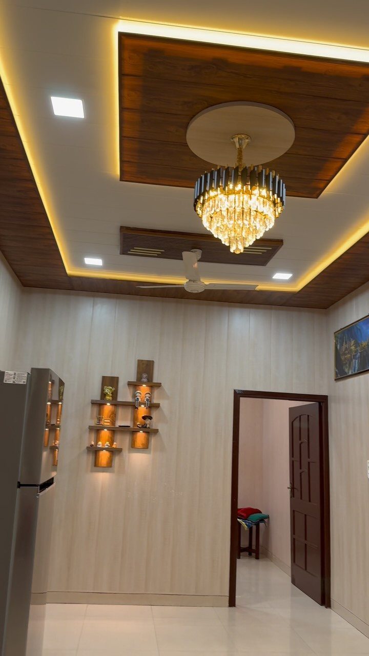 Modern multi-level ceiling with dark wood veneered panels and a gold crystal chandelier.