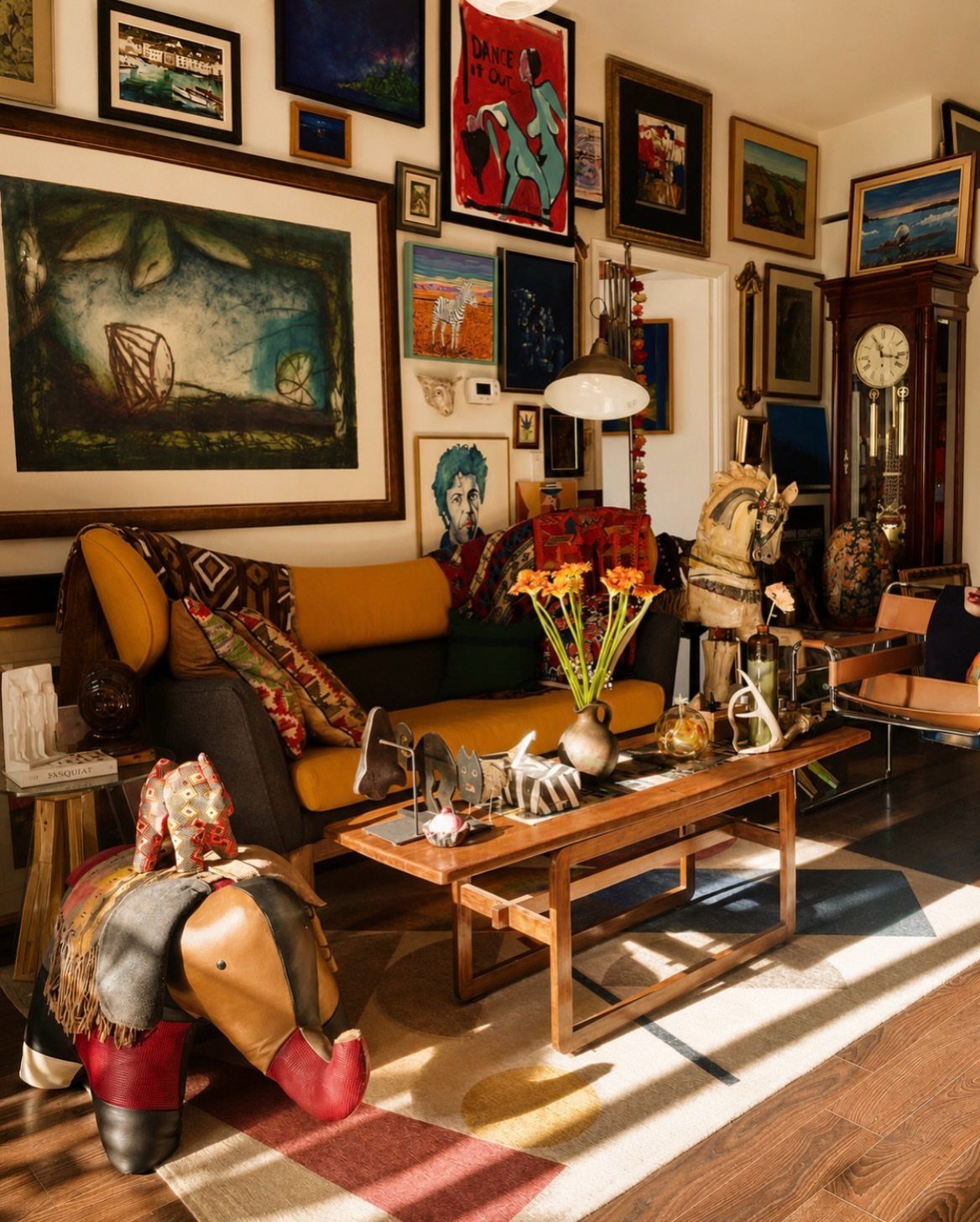 Eclectic living room with a yellow sofa and walls covered in framed artwork.