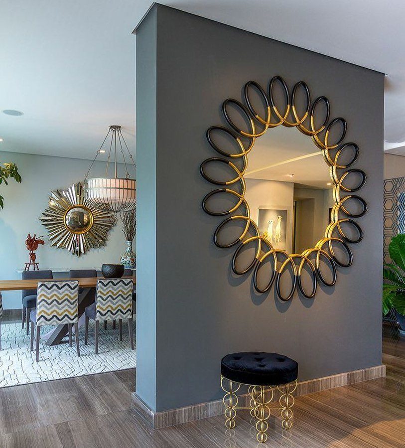 Round decorative mirror with gold and black frame on a grey wall