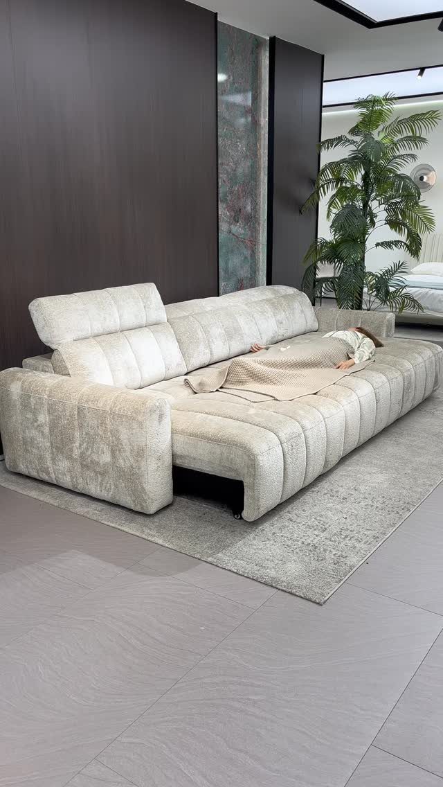 Light ribbed sofa used as a bed with a person sleeping on it.
