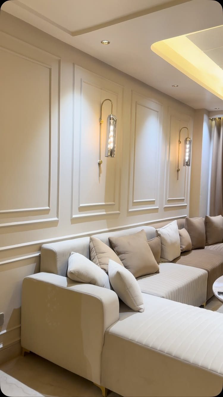 Beige sectional sofa with cushions against a cream wall with decorative molding.
