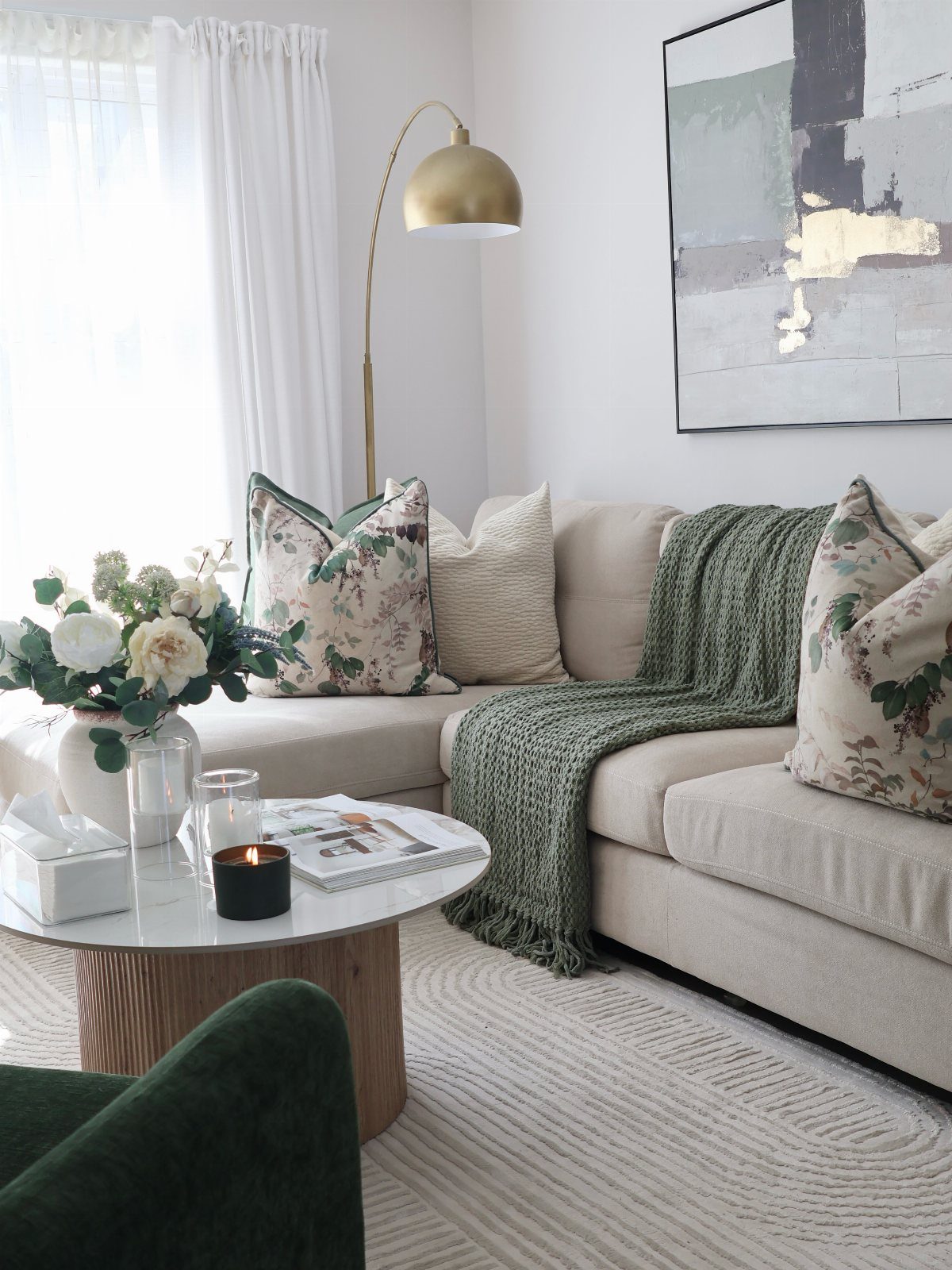 Bright living room with white sheer curtains, beige sofa, and gold arc lamp.