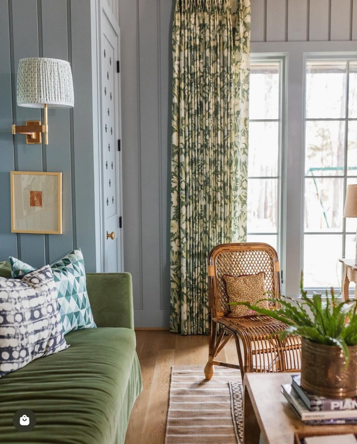Green patterned floor-to-ceiling curtains in a living room with a green velvet sofa.