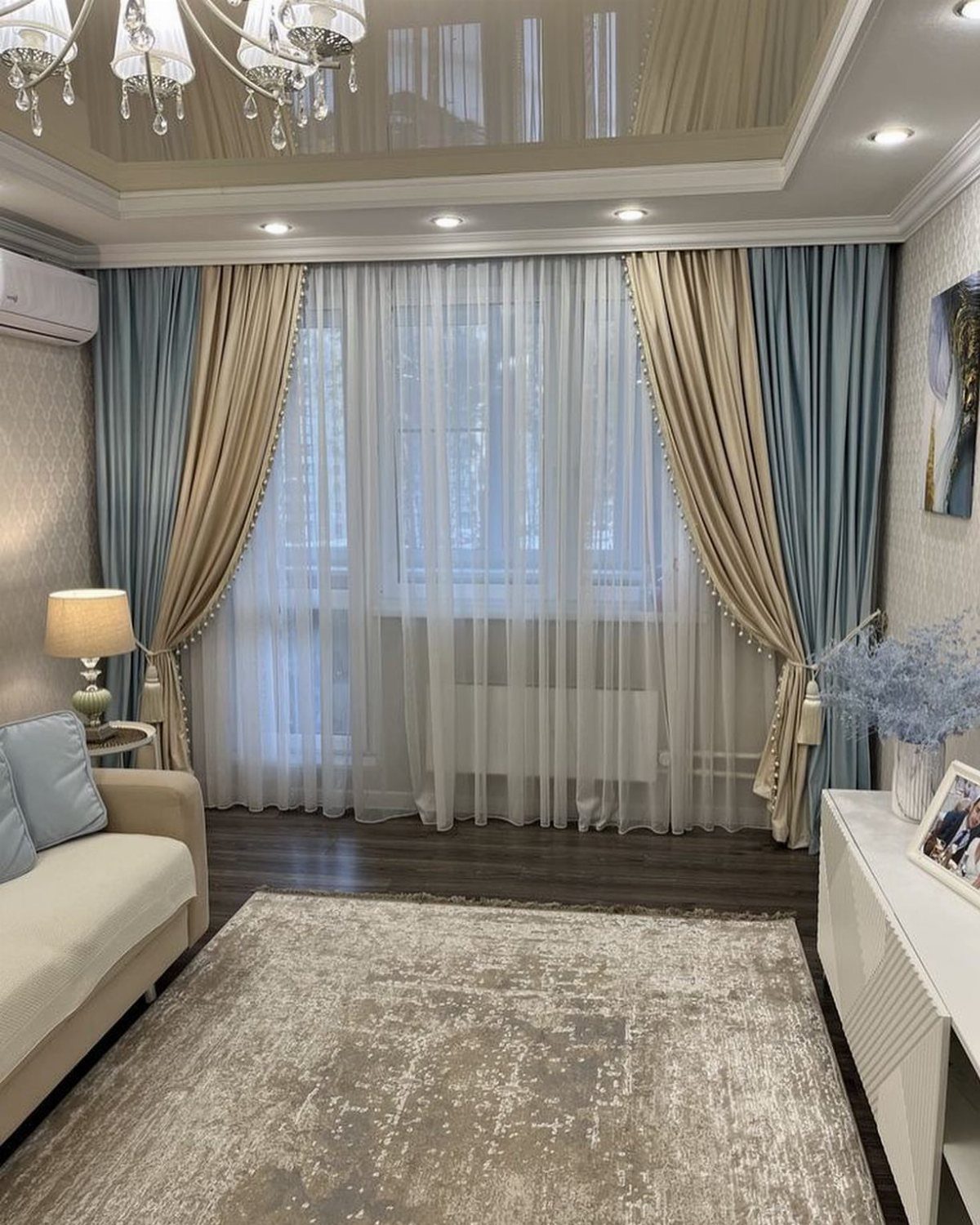 Blue and beige two-tone curtains draped over white sheers in a living room.