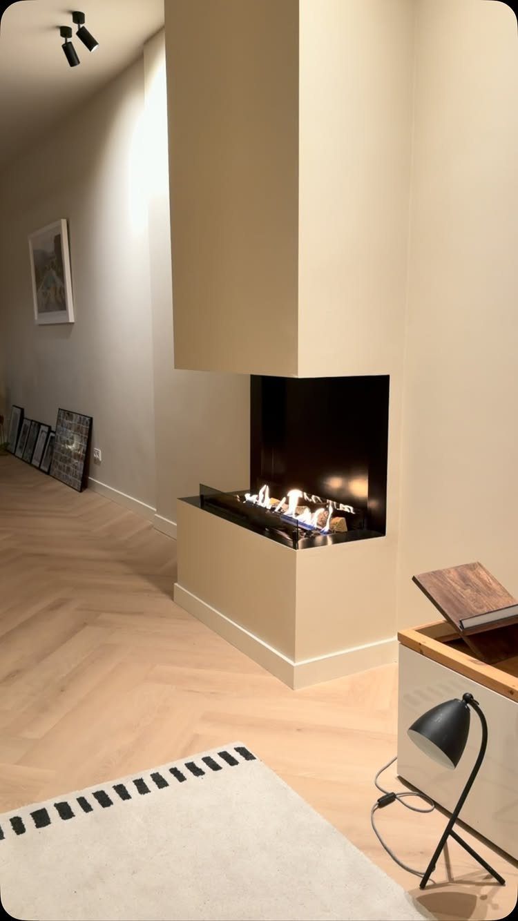 Modern bioethanol fireplace built into a beige wall with light herringbone wood flooring.