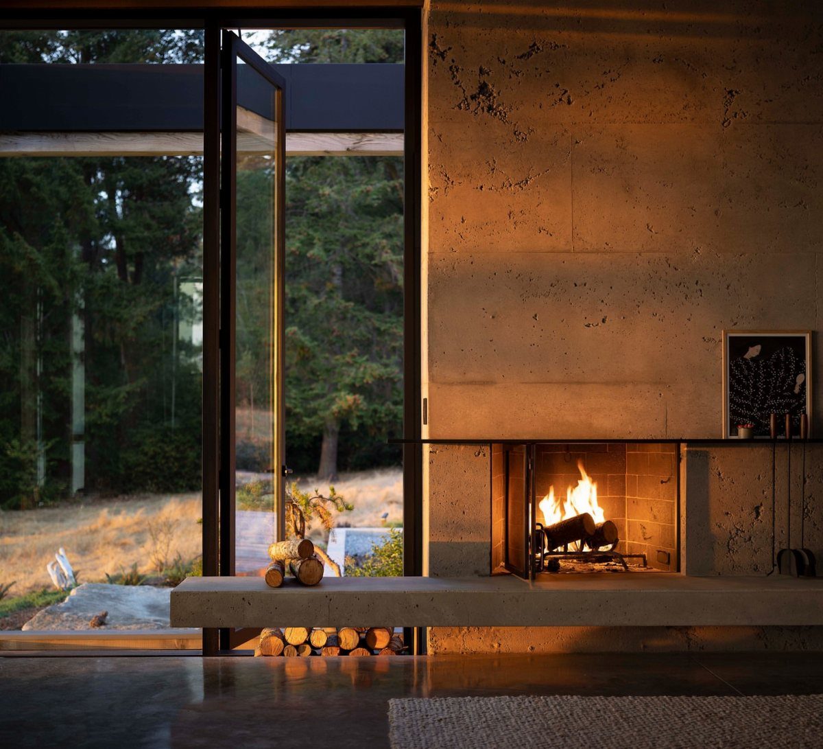 Modern fireplace embedded in a textured grey concrete wall with a burning fire.