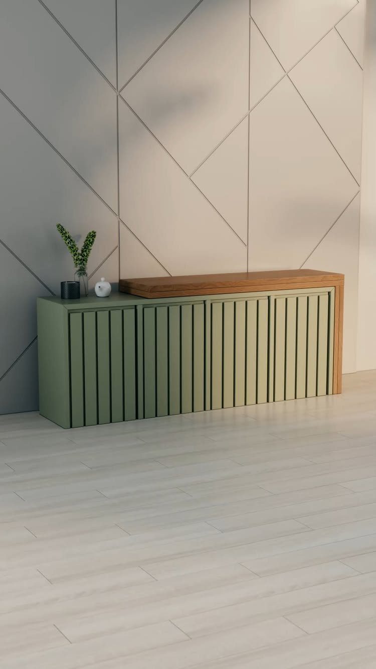 Green slatted sideboard with wooden top against a geometric grey wall.