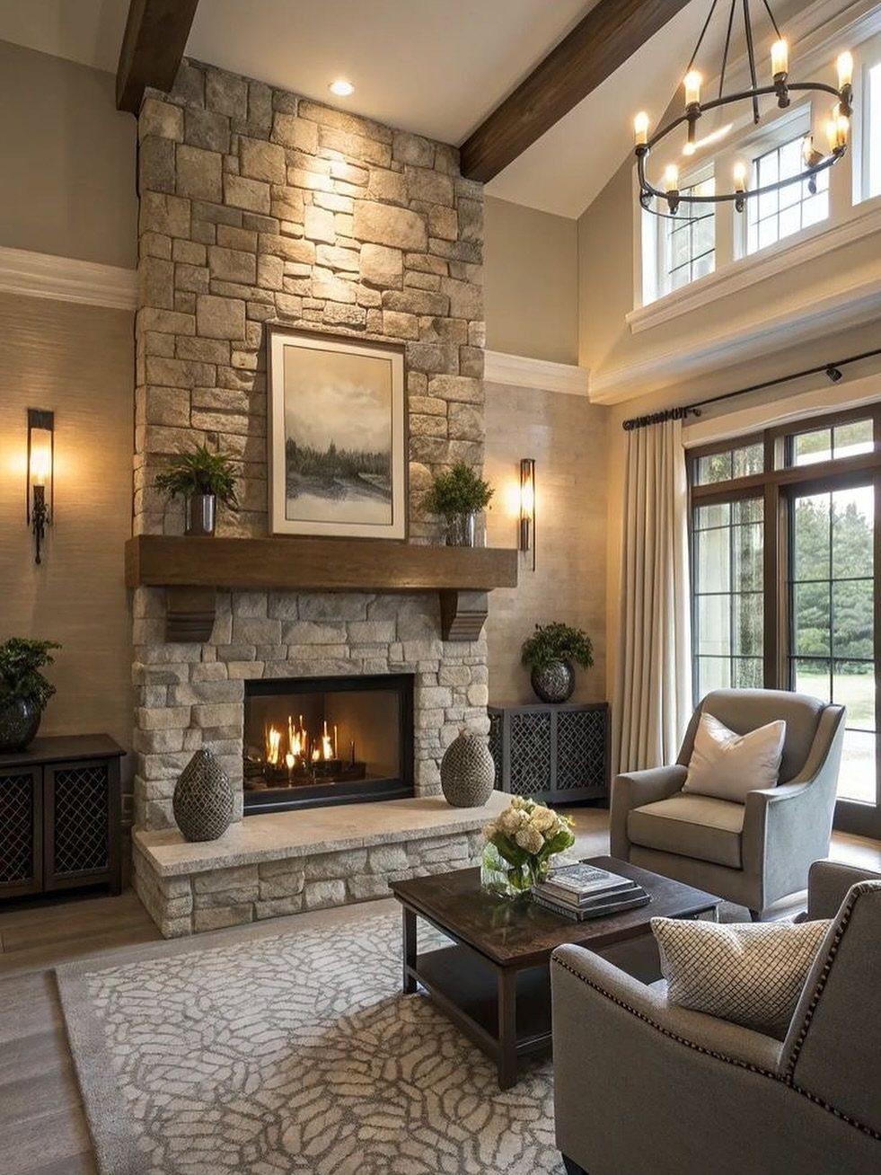 Stone fireplace with wooden mantel and two grey armchairs around a coffee table.