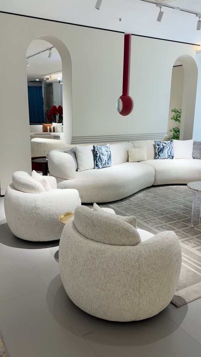 Two rounded white accent chairs positioned in front of a curved white modular sofa.