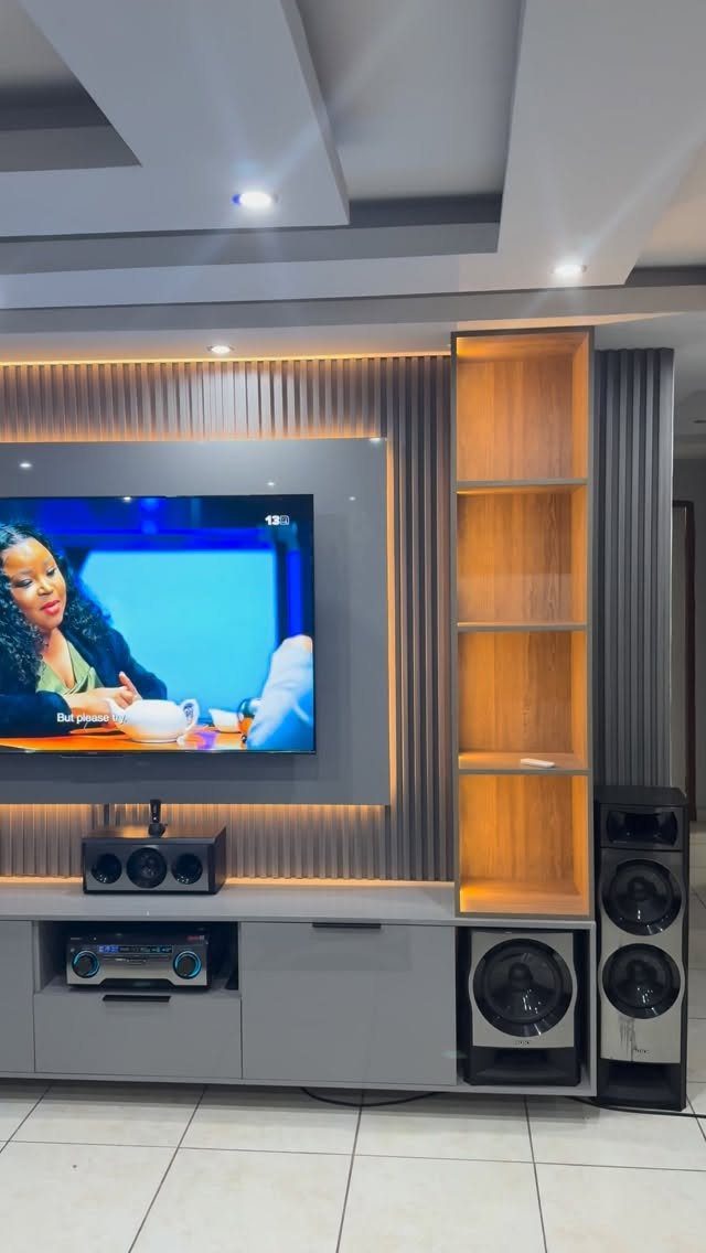 Wall-mounted television with a grey media console and integrated wooden shelving unit.