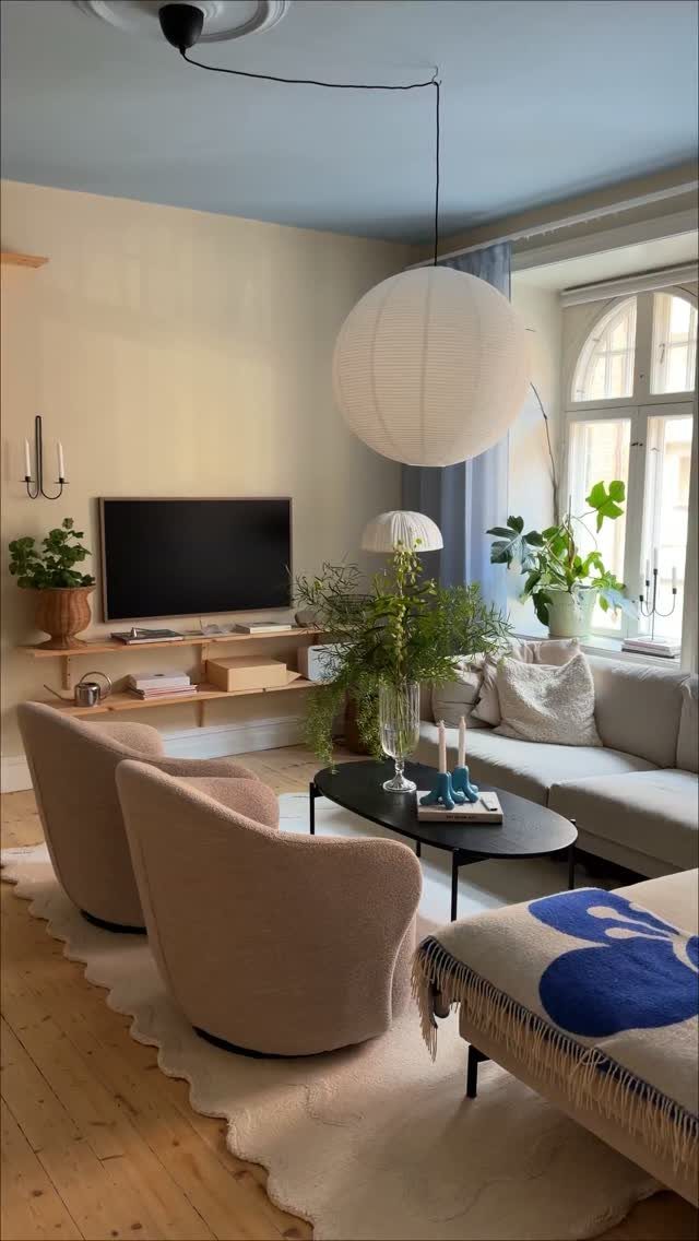 Living room with beige armchairs and a white scalloped area rug on wood floors.