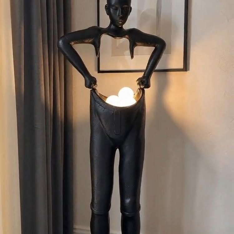 Sculptural black human figure floor lamp with glowing white bulbs inside the torso.