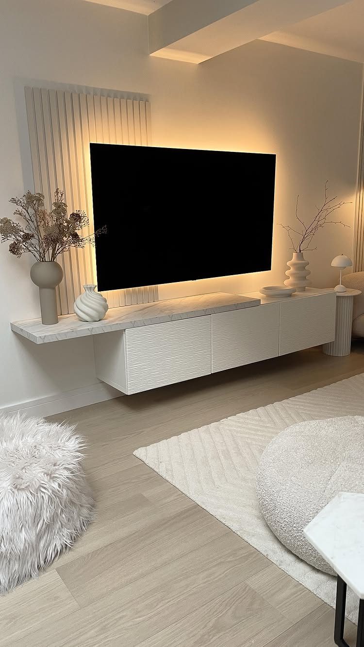 Black flat-screen TV with warm yellow backlighting mounted above a white floating console.