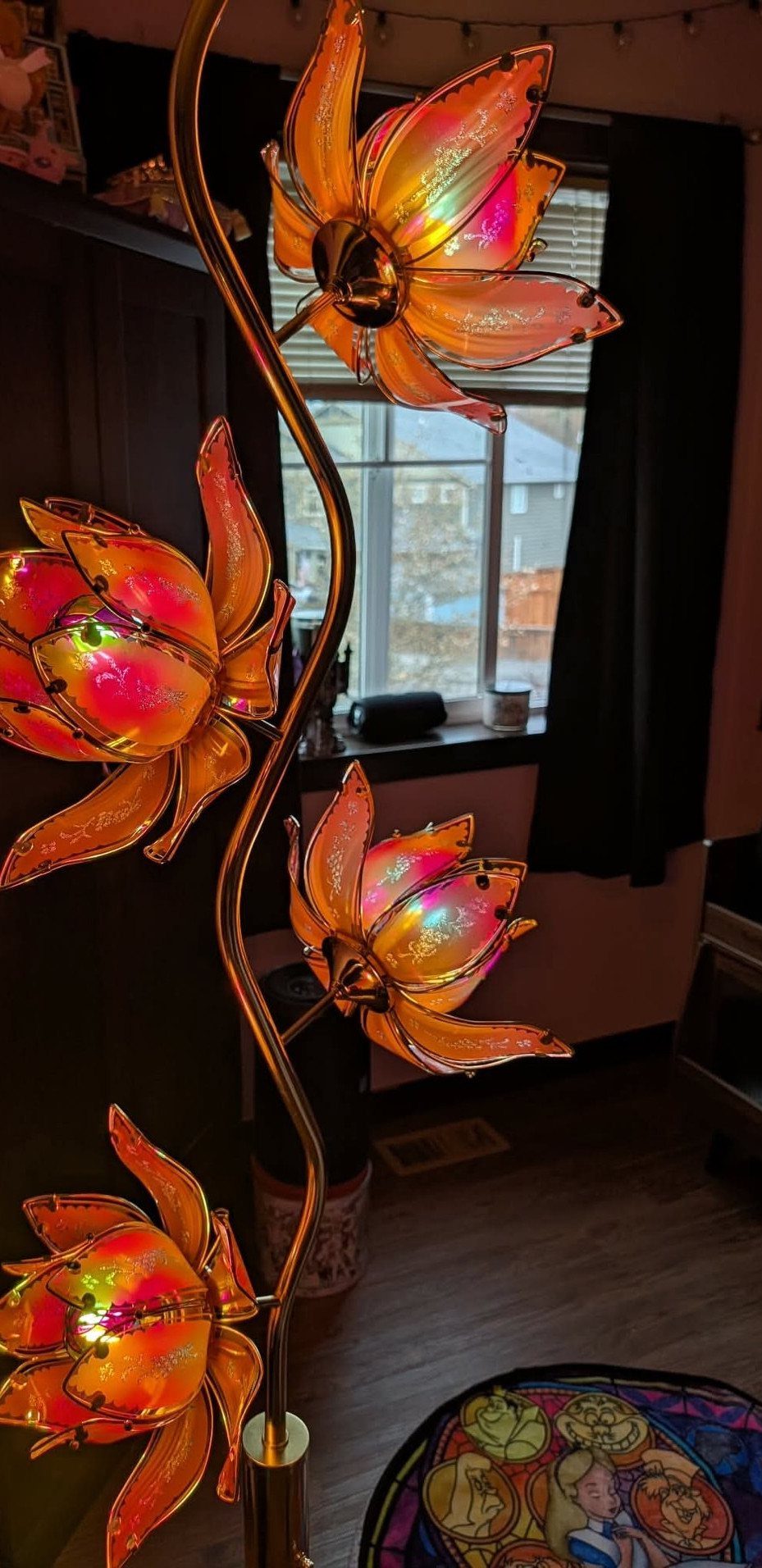 Colorful lotus-shaped floor lamp with glowing orange and pink petals in a room.
