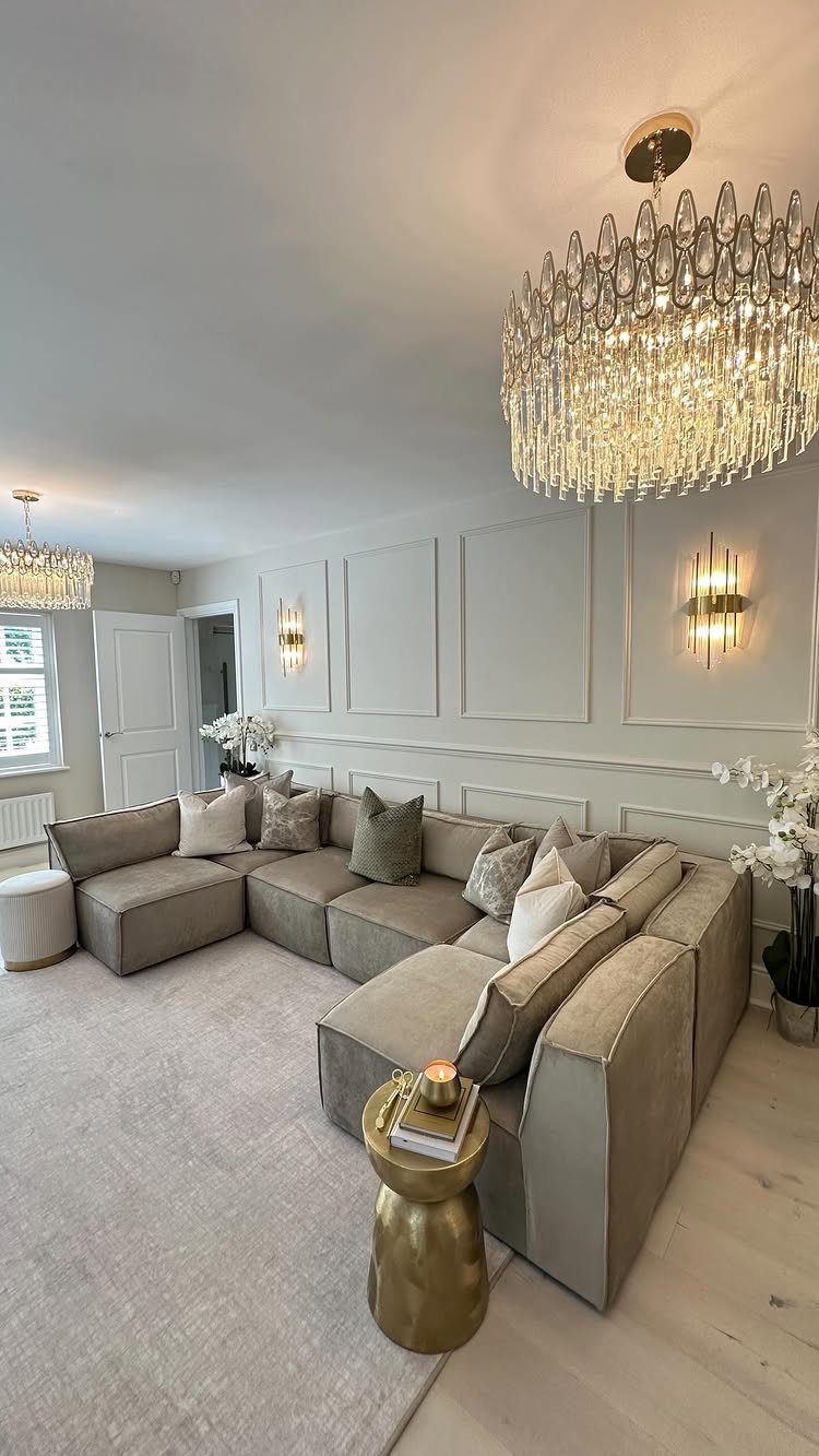 Crystal chandelier hanging in a modern living room with a grey sectional sofa.