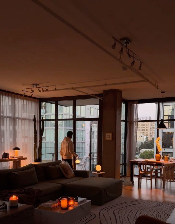 Modern living room with small glowing portable lamps on tables and a grey sofa.