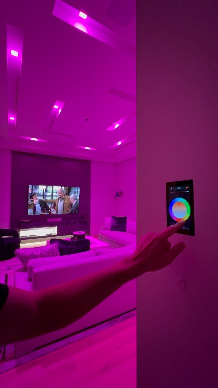 Hand adjusting a digital color wheel controller for purple living room ambient lighting.