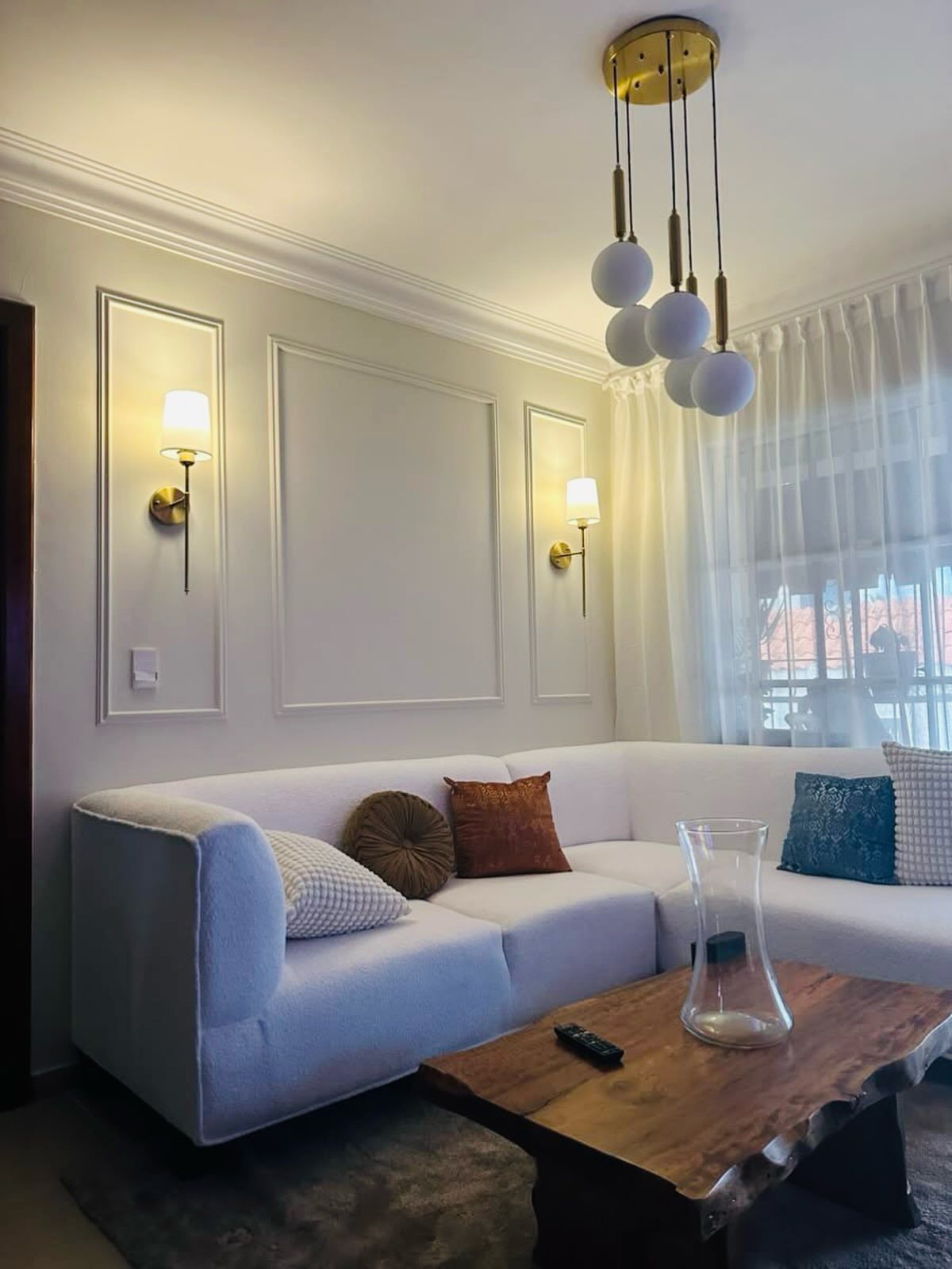 Two gold wall sconces with white shades mounted on a white paneled wall.