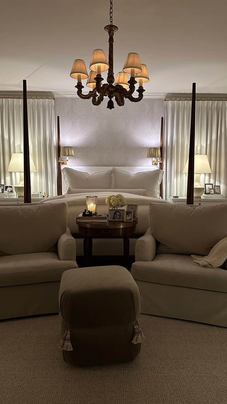 Two beige armchairs and an ottoman forming a seating area in a bedroom.