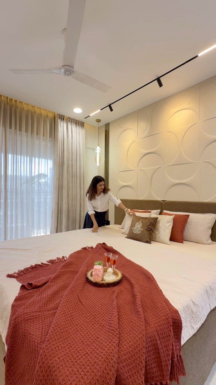 Beige floor-to-ceiling curtains in a modern bedroom with a white textured wall.