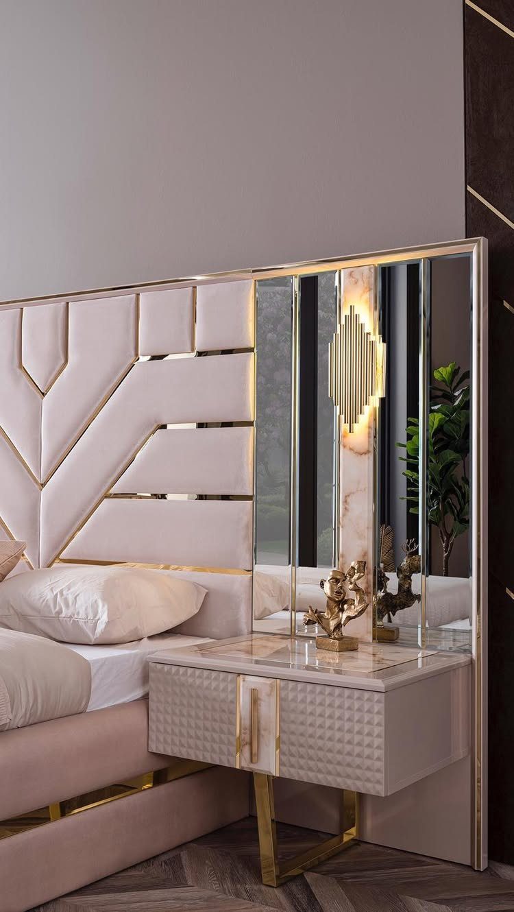 Tall upholstered pink headboard with gold accents and a matching marble bedside table.