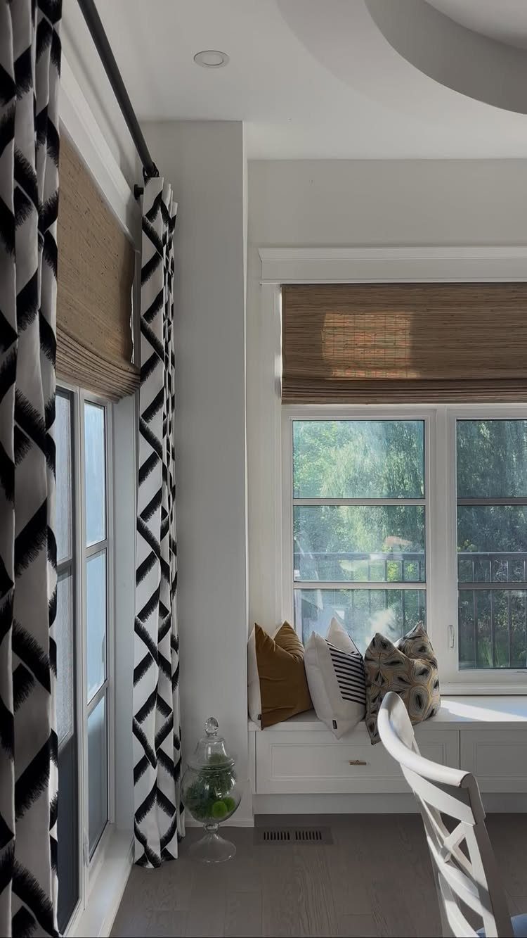 White window trim with brown woven bamboo shades and a cozy window seat.