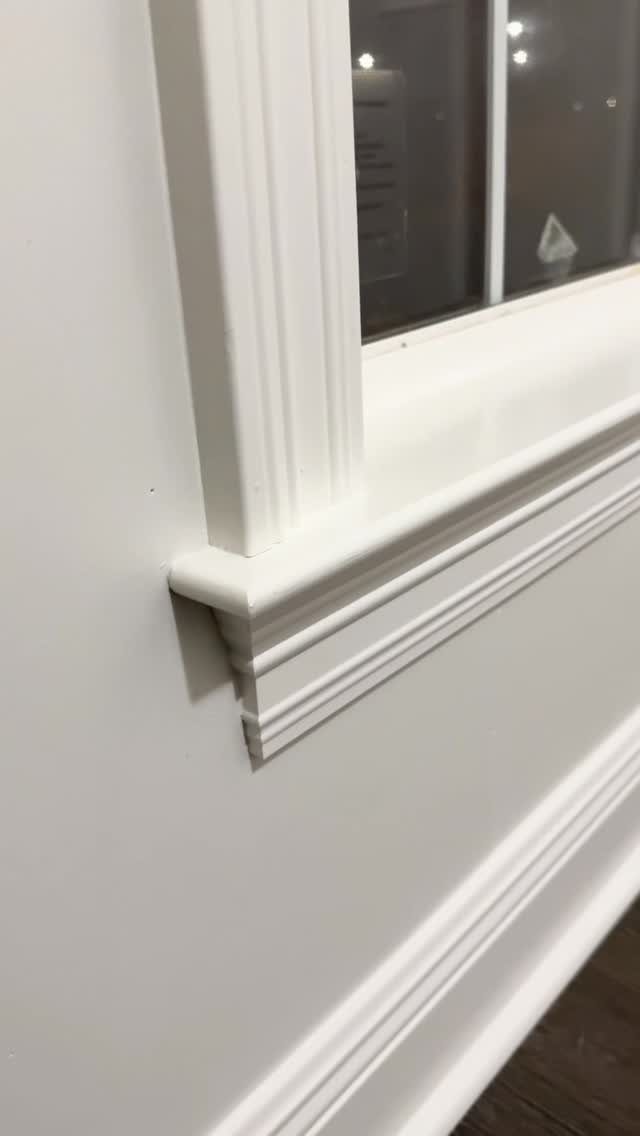 White molded window trim and baseboard installed on a clean white wall.