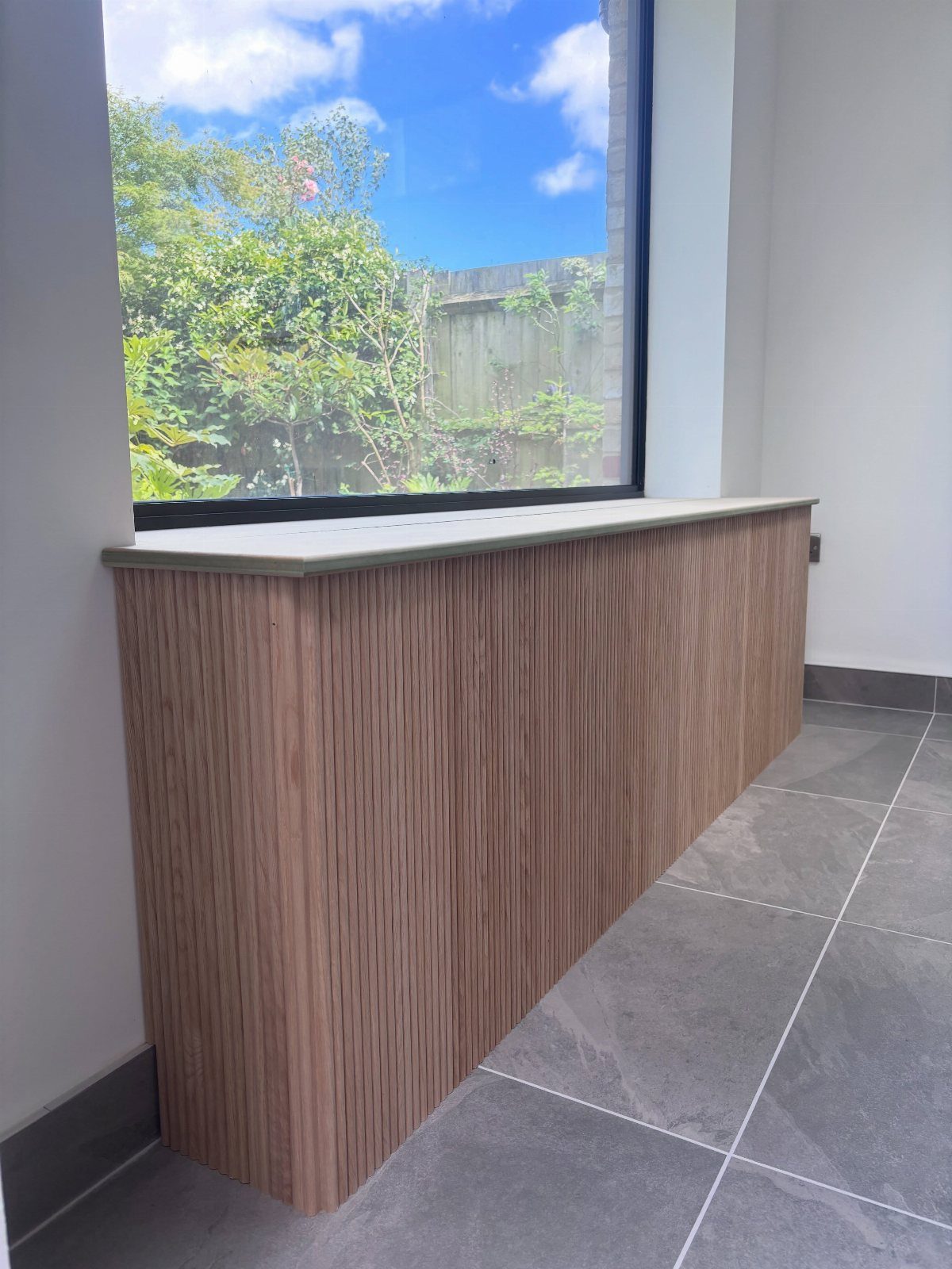 Window with a wide extended wooden ledge and black frame in a modern room