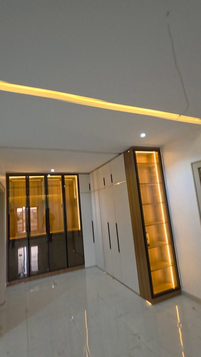 Modern white built-in wardrobe with a tall glass display cabinet and warm interior lighting.