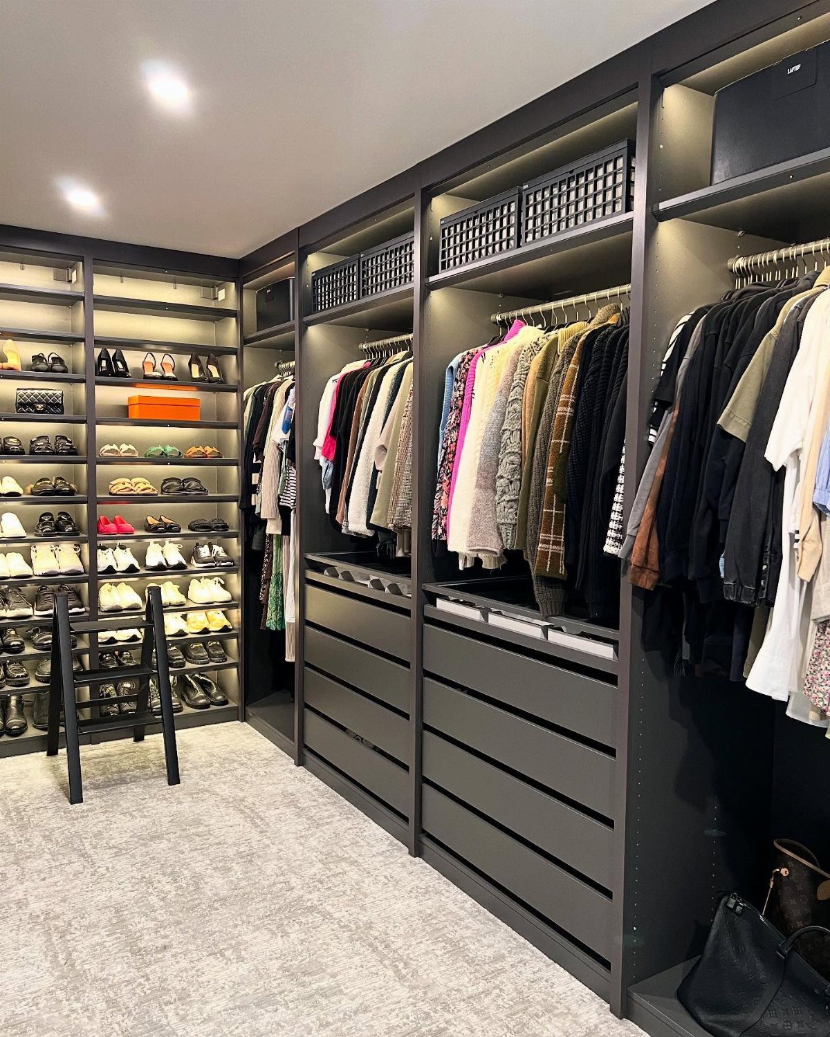 Modern dark grey open closet system with hanging clothes and organized shoe shelves.