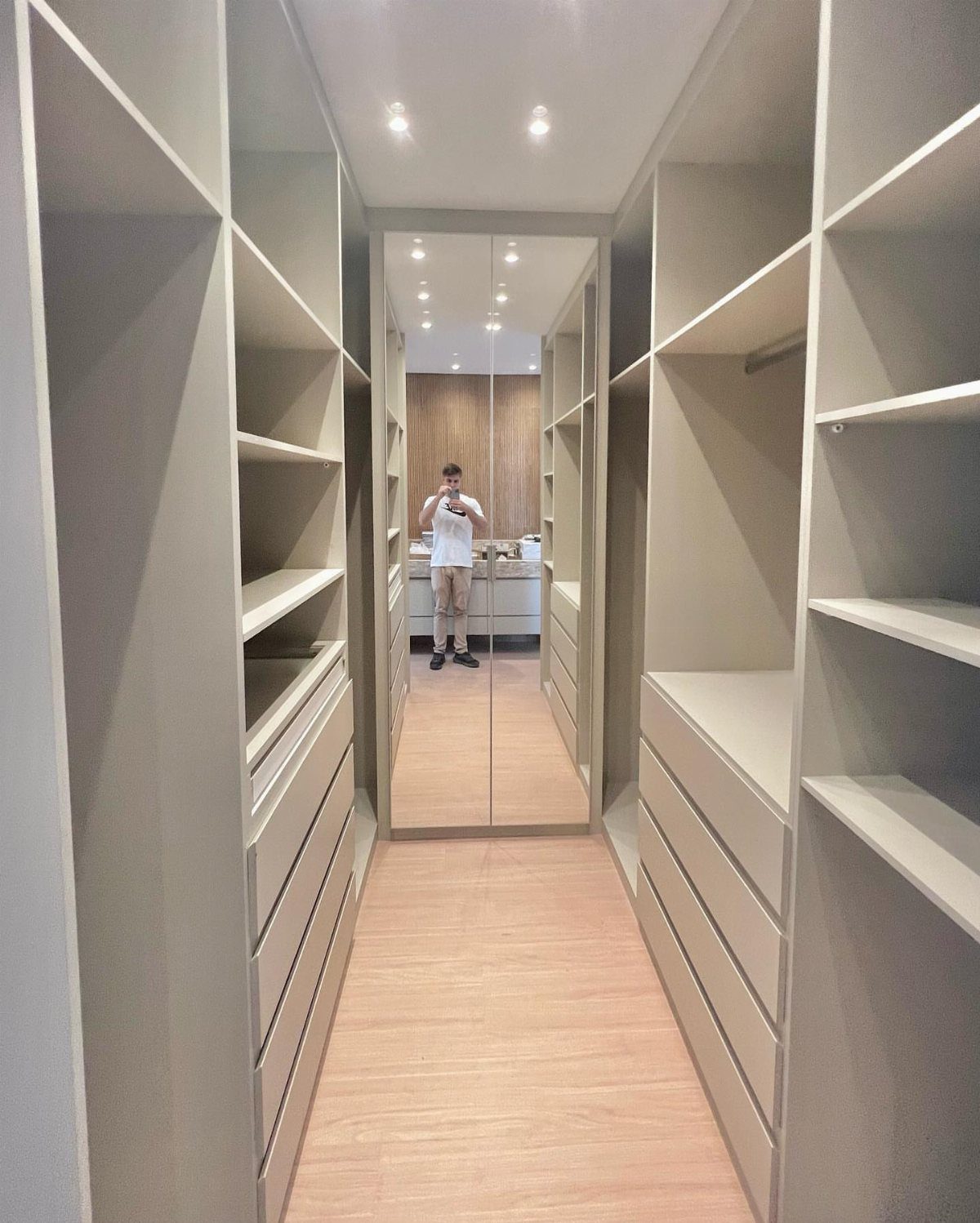 Full-length mirror at the end of a modern grey open walk-in closet hallway.