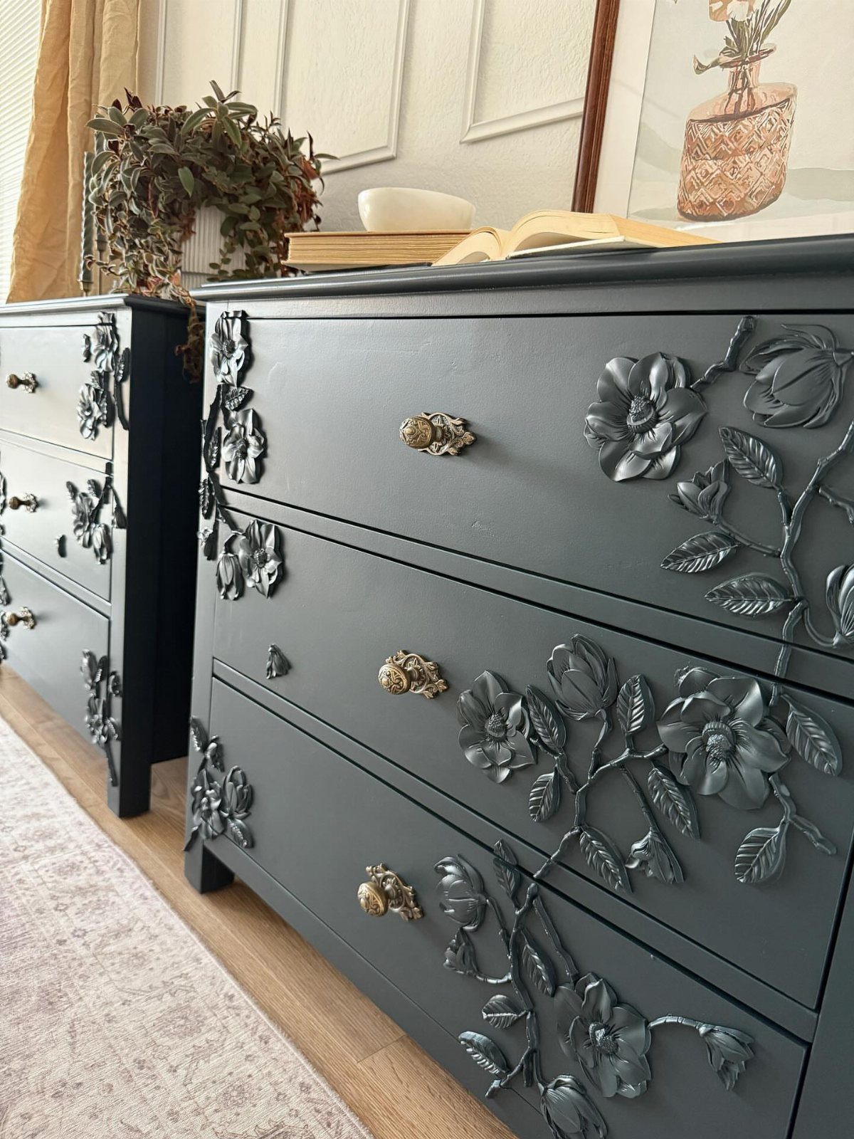 Dark grey dressers with ornate 3D floral carvings and gold knobs in a bright room.
