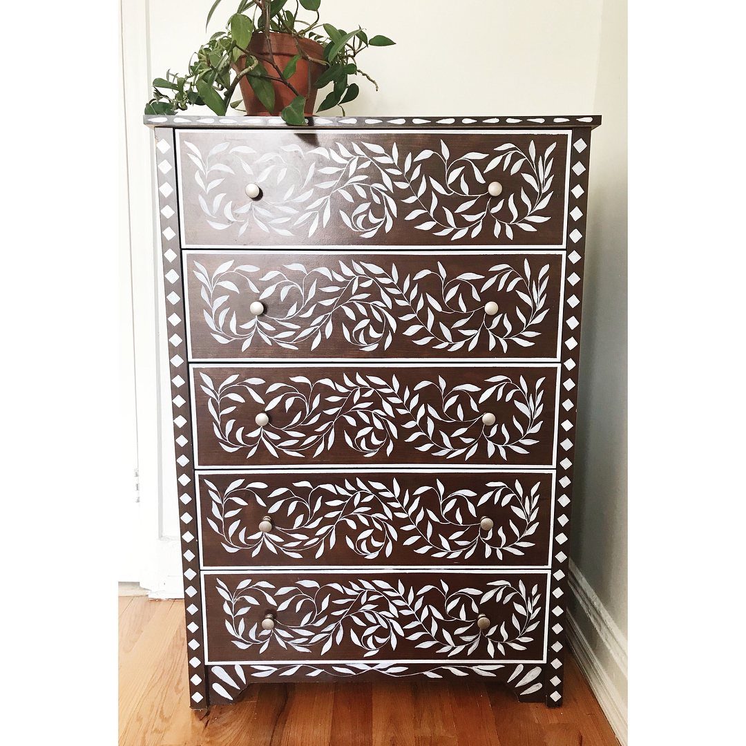 Dark brown dresser with white painted floral bone inlay style patterns and borders.