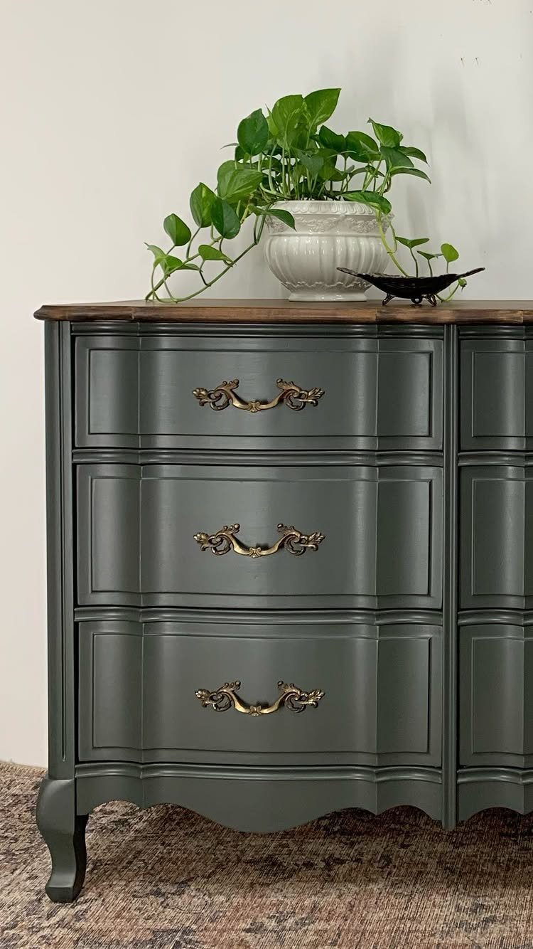 Dark grey French Provincial dresser with ornate gold handles and a wooden top.