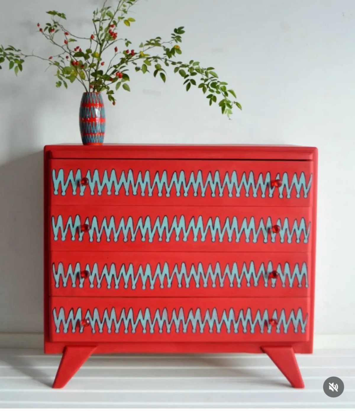 Red dresser with light blue and white geometric zigzag patterns on drawer fronts.
