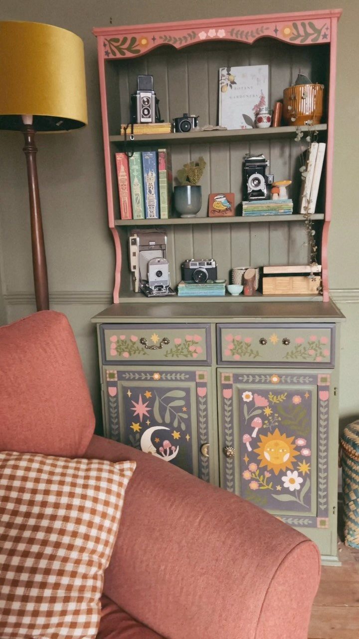 Vintage hutch with pink top and sage green base featuring painted floral designs.