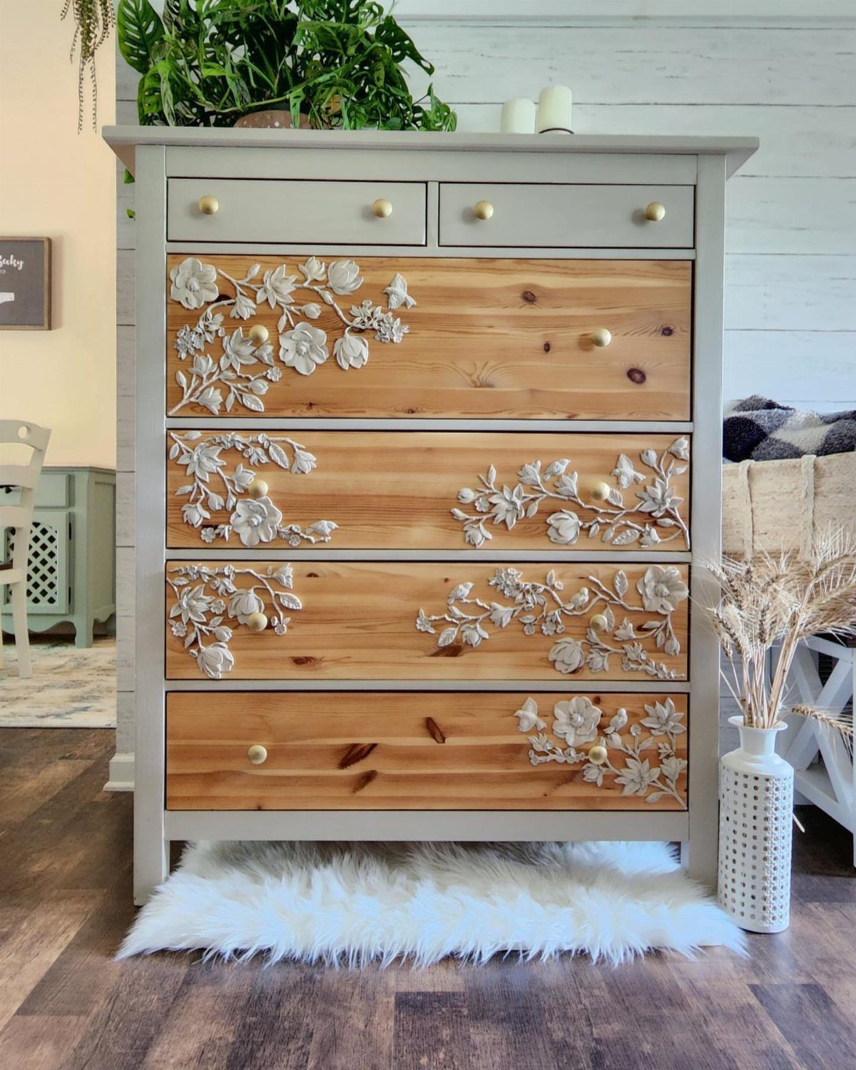Grey painted dresser with natural wood drawers featuring raised floral carvings.